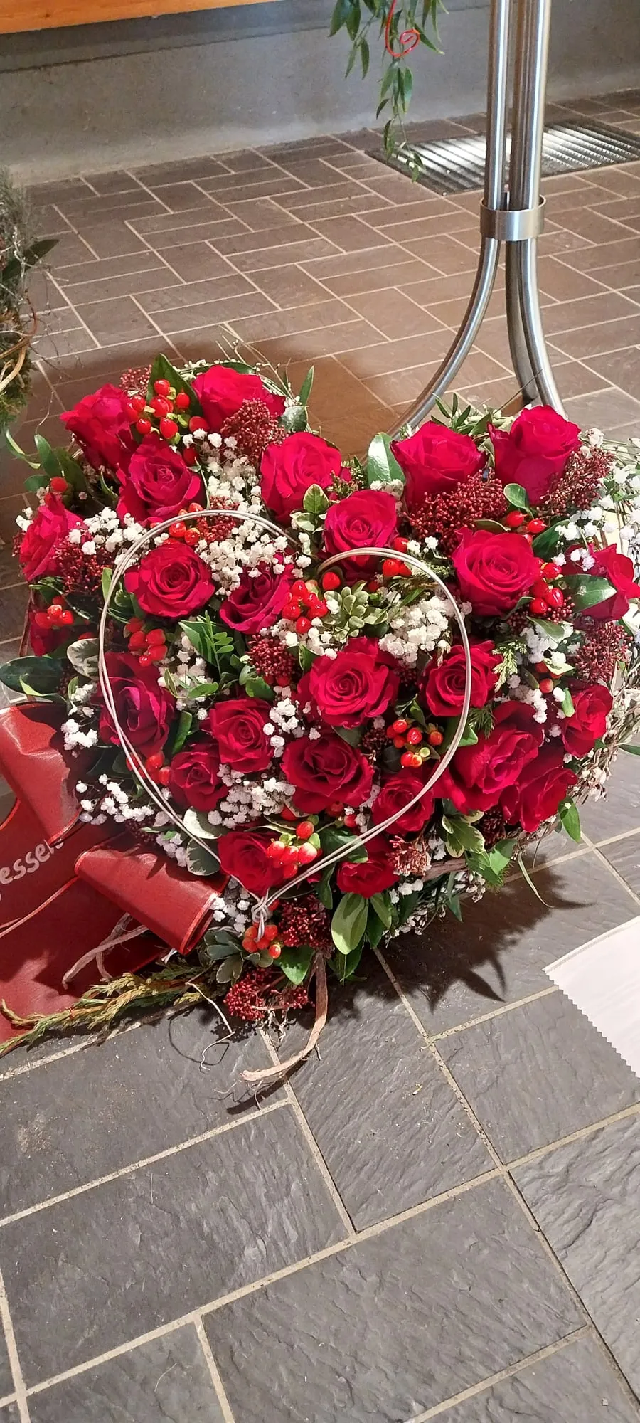 Herz aus roten Rosen mit geschwungenem Metallbogen