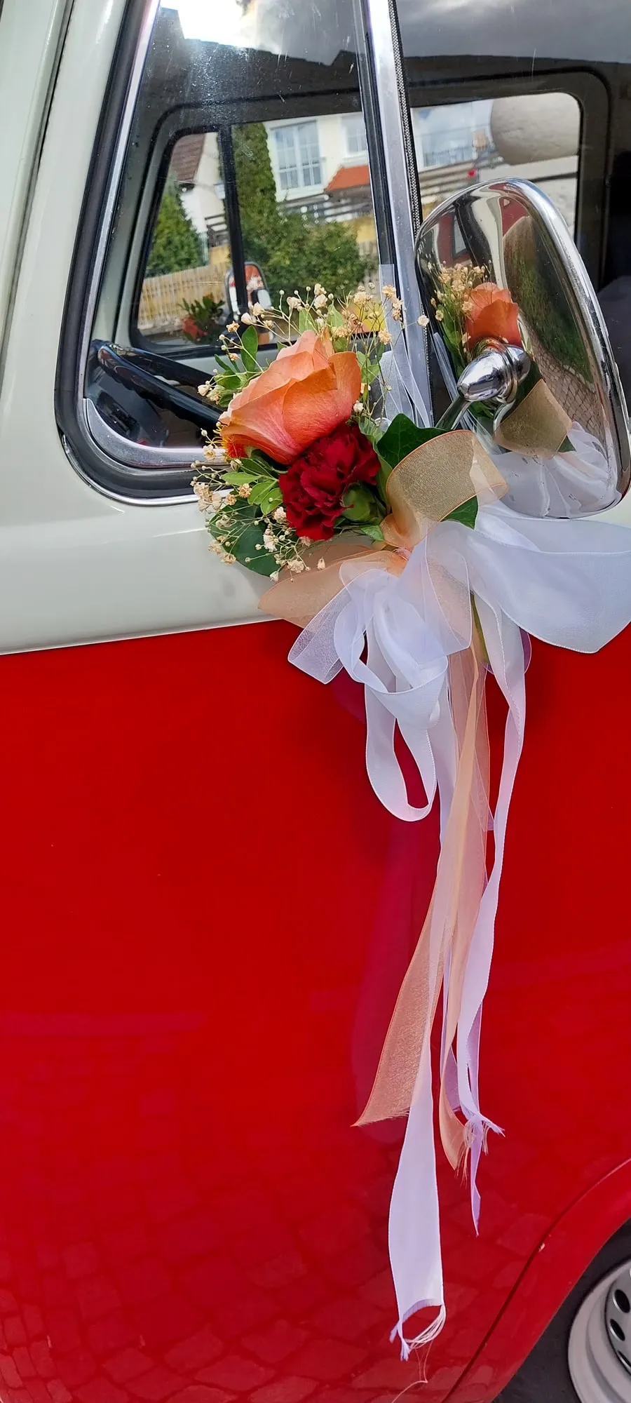 Autoschmuck mit weißen Bändern und roter Rose auf der Motorhaube