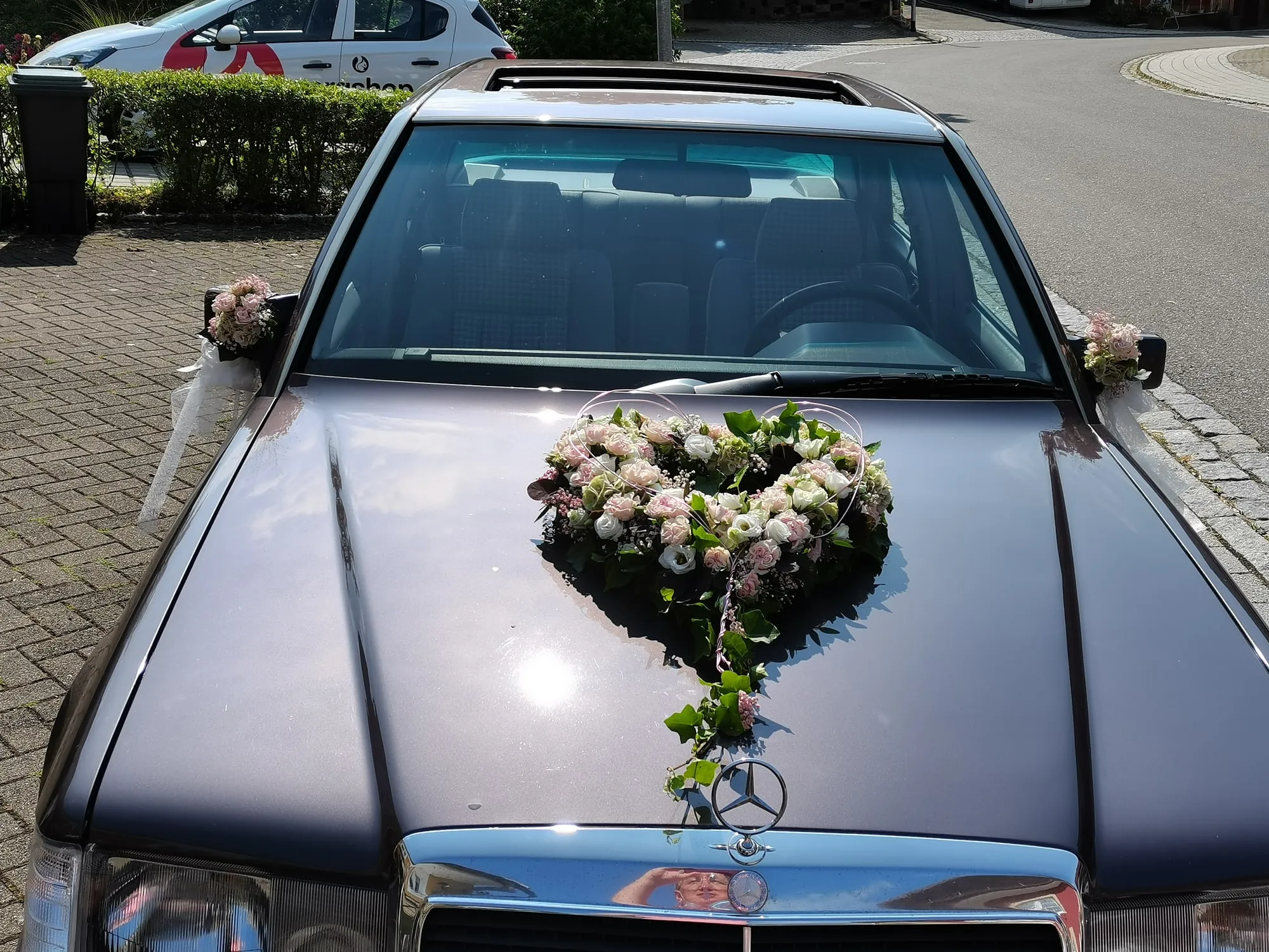 Herzförmiger Blumenschmuck auf der Motorhaube eines Hochzeitsautos