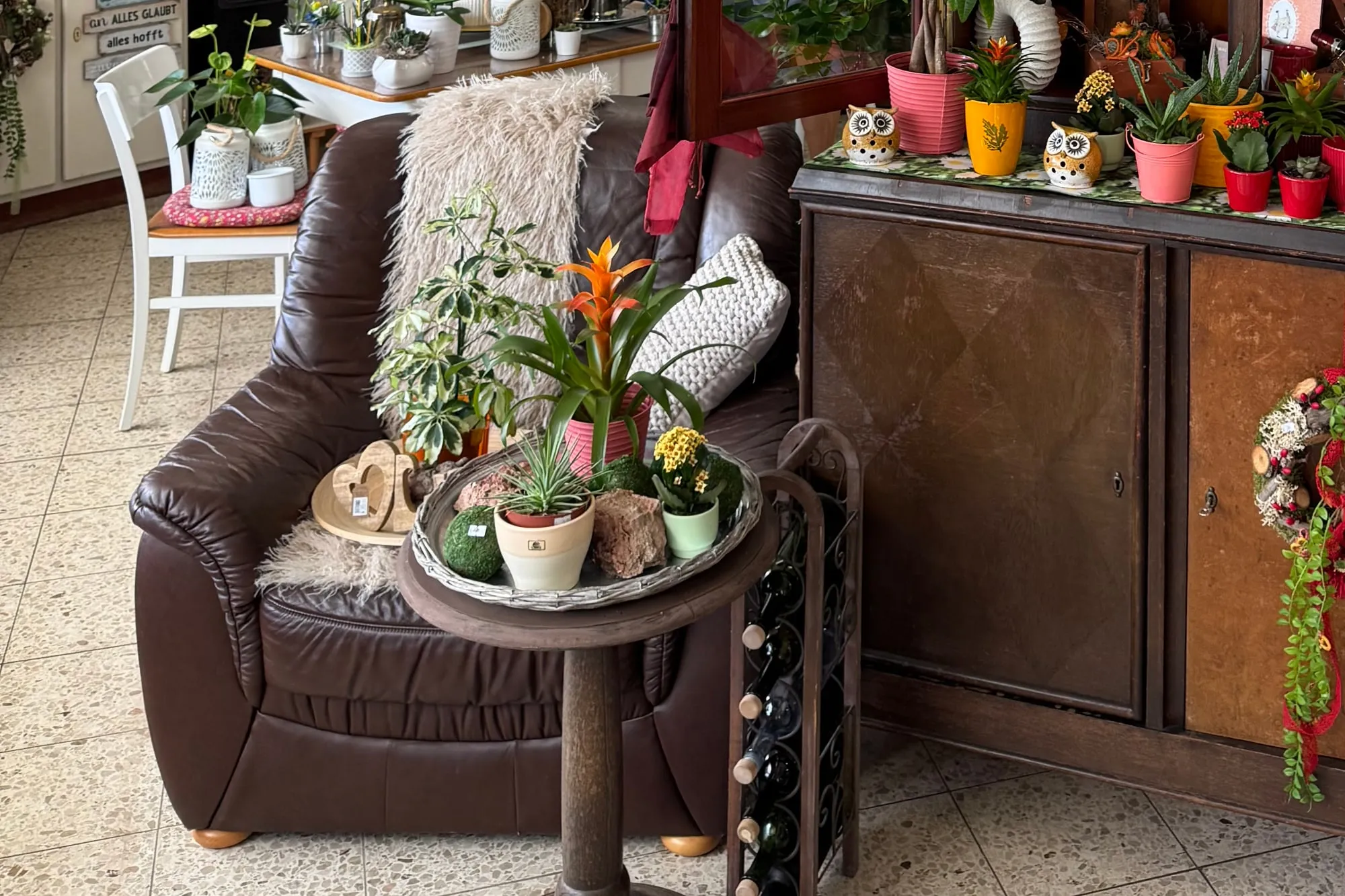 Die Sitzecke im Laden: Ledersofa, Beistelltisch mit bepflanzter Schale und eine Kommode voller Topfpflanzen